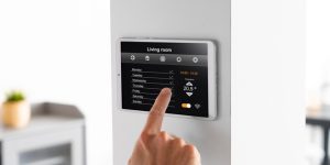 Person adjusting smart home thermostat on wall.