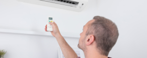 Man adjusting air conditioner settings with remote